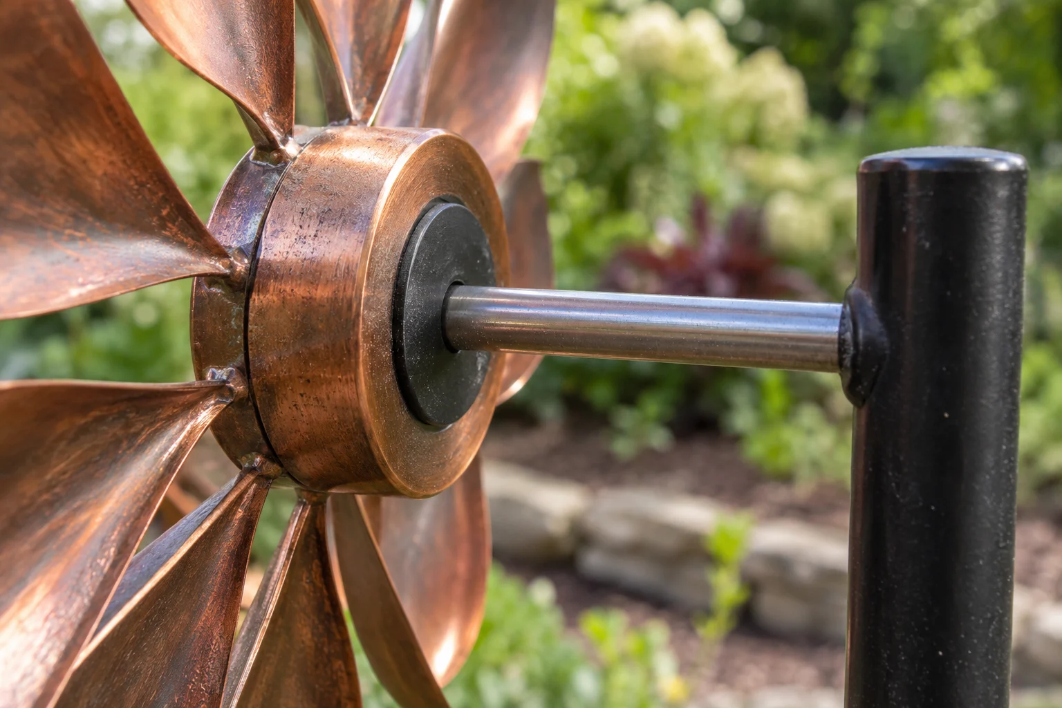 Close view of a metal shaft entering a dark circular cap at the rear of a copper-colored rotor hub